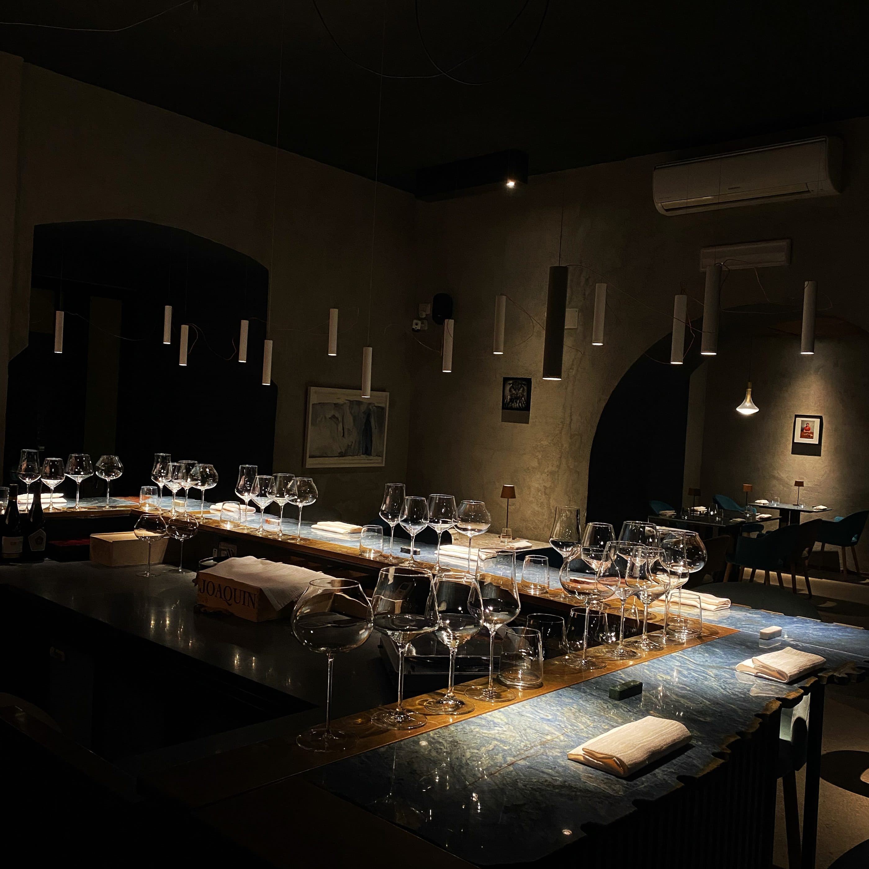 Il bancone della cantina nella penombra, con decine di calici allineati sul piano di marmo