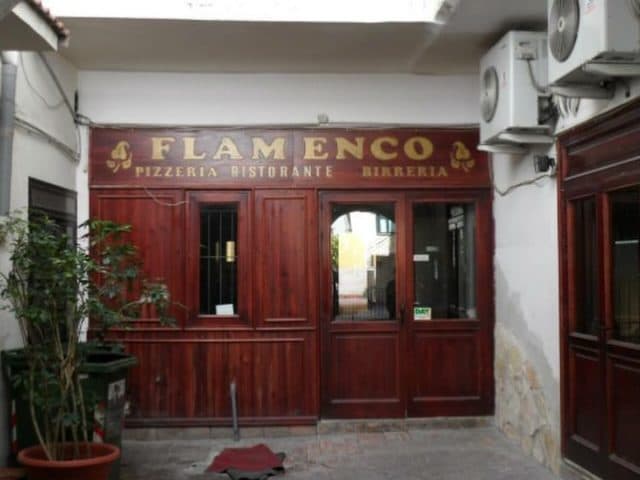 L'insegna del Flamenco, la pizzeria che occupava questi locali prima di Hydra: vetrina e porte di legno laccato rosso in fondo al vicolo